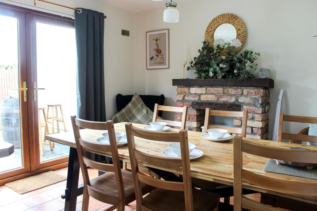 Un coin repas agrémenté d’une cheminée en briques, de chaises en bois et d’une table dressée pour quatre personnes.