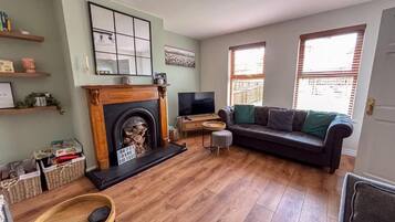 A living room with a fireplace, a sofa, a television, and a wooden floor.