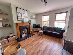 Un salon avec une cheminée, un canapé, un téléviseur et un plancher en bois.
