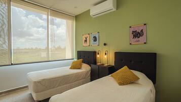 A room with two beds, a window, and wall-mounted artwork.