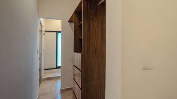 A narrow hallway with a wooden wardrobe and a door leading to another room.