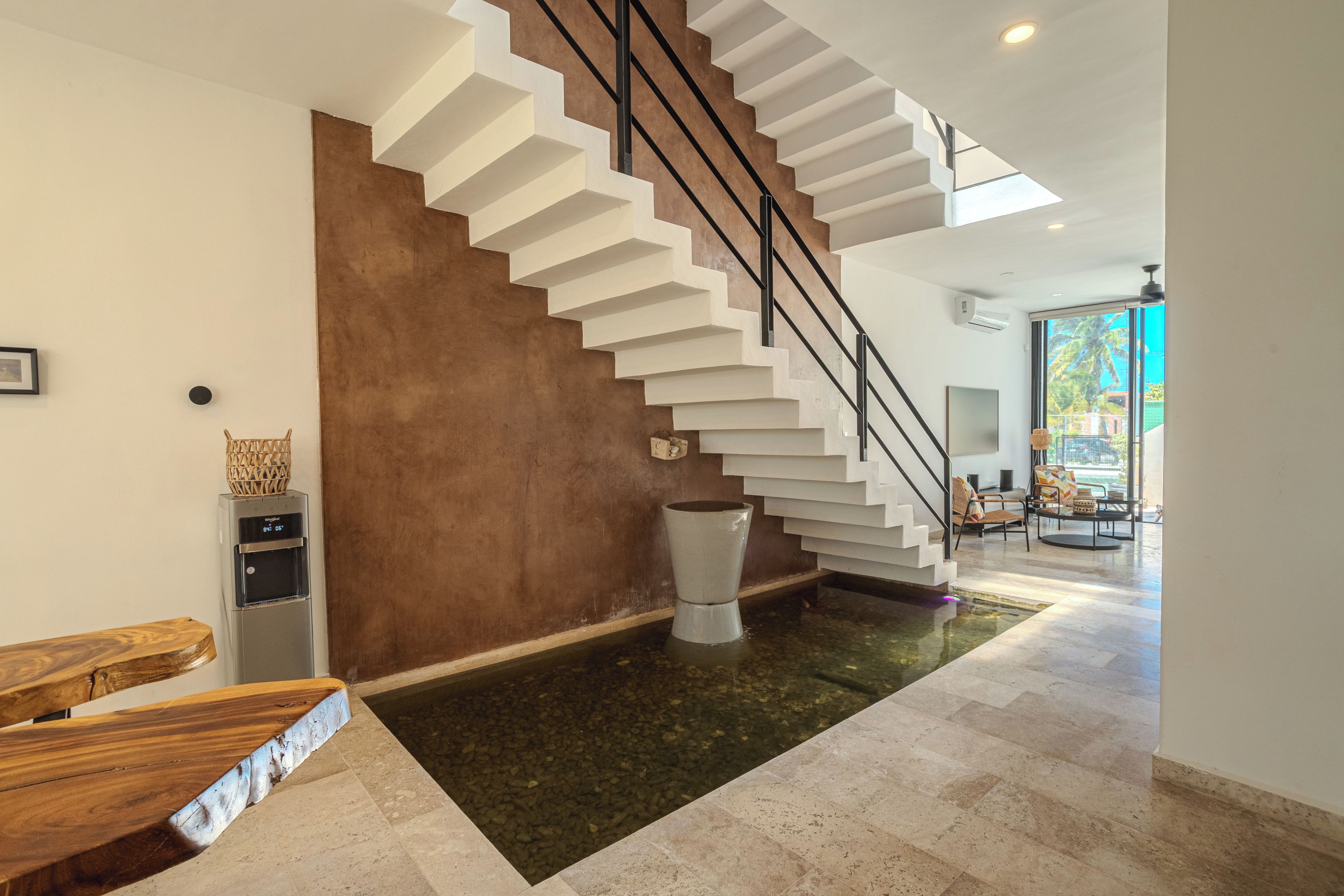 A modern interior with a staircase, a water feature, and a seating area.