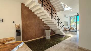 A modern interior with a staircase, a water feature, and a seating area.