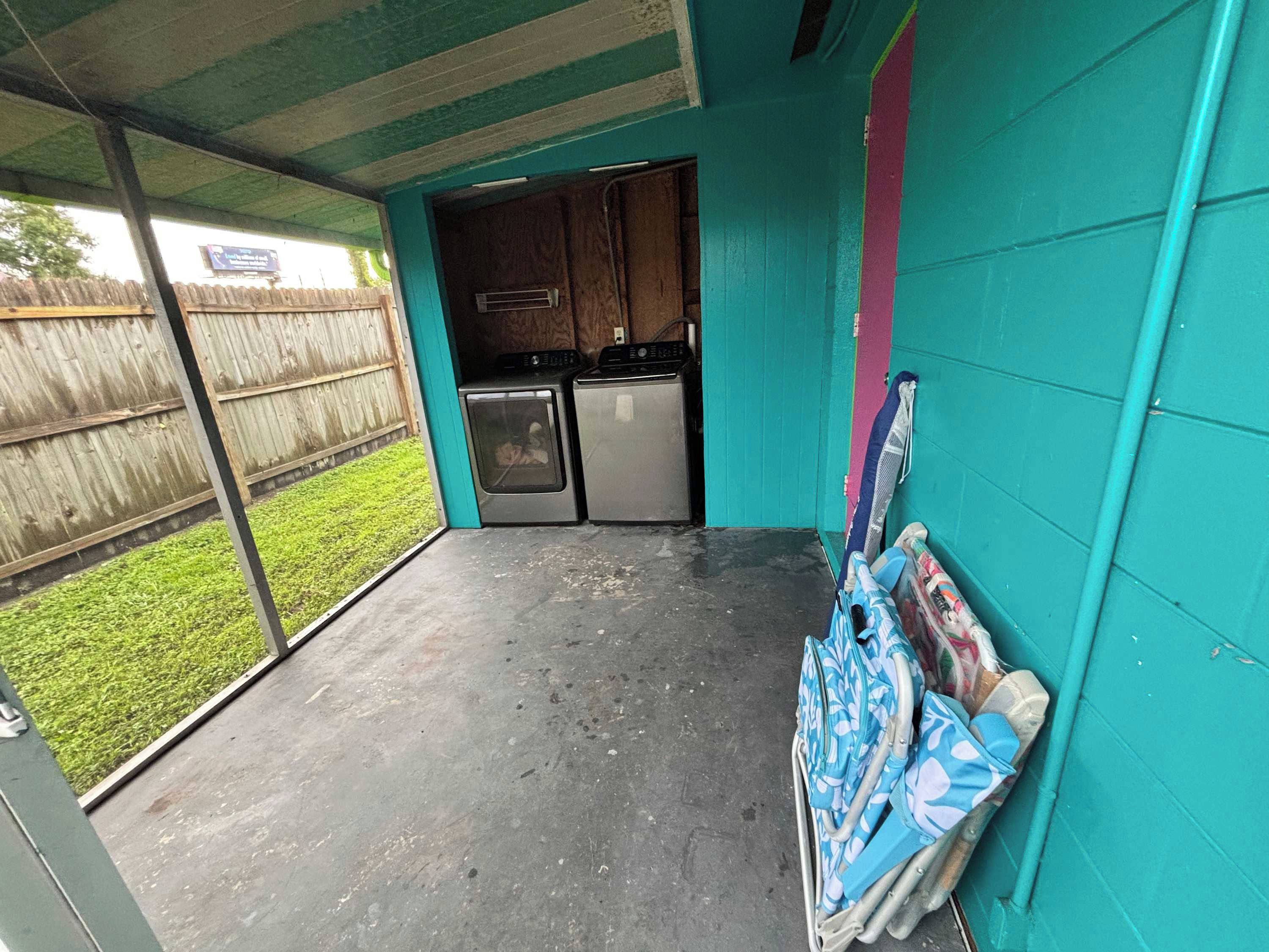 Un espace extérieur abrité, doté d’une cuisine et d’un petit jardin visible à travers la porte ouverte.