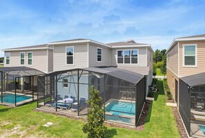 A residential property with a swimming pool, enclosed patio areas, and a well-maintained lawn. - 100" TV - Pool, Spa & Epic Game Room Villa for 14! (Kissimmee)