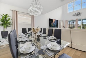 Una sala menjador moderna amb taula de vidre preparada per a dinar, envoltada de cadires.