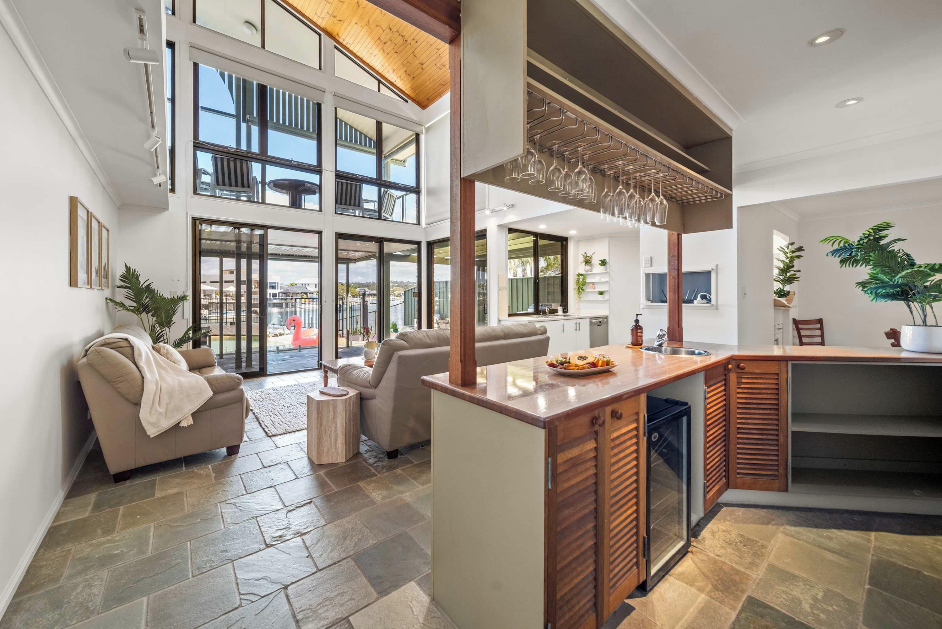 A spacious living area with a large glass door leading to a balcony, a kitchen with a wooden island, and a seating area with a sofa and a coffee table.