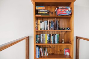 Una prestatgeria de fusta amb diversos llibres i jocs.