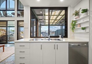 Eine moderne Küche mit großem Fenster, weißen Schränken und einem integriertem Geschirrspüler.