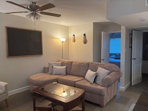 A living room with a sectional sofa, a glass-top coffee table, a floor lamp, a ceiling fan, and a framed artwork on the wall. - Top-Floor Scottsdale Retreat - Pool, Spa & Near Old Town (Scottsdale)
