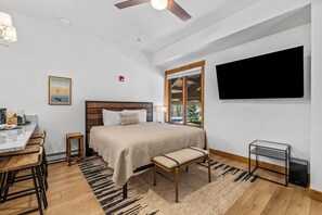 Ein Schlafzimmer mit einem Bett, einem Schreibtisch, einem Stuhl, einem Fernseher und einem Fenster.