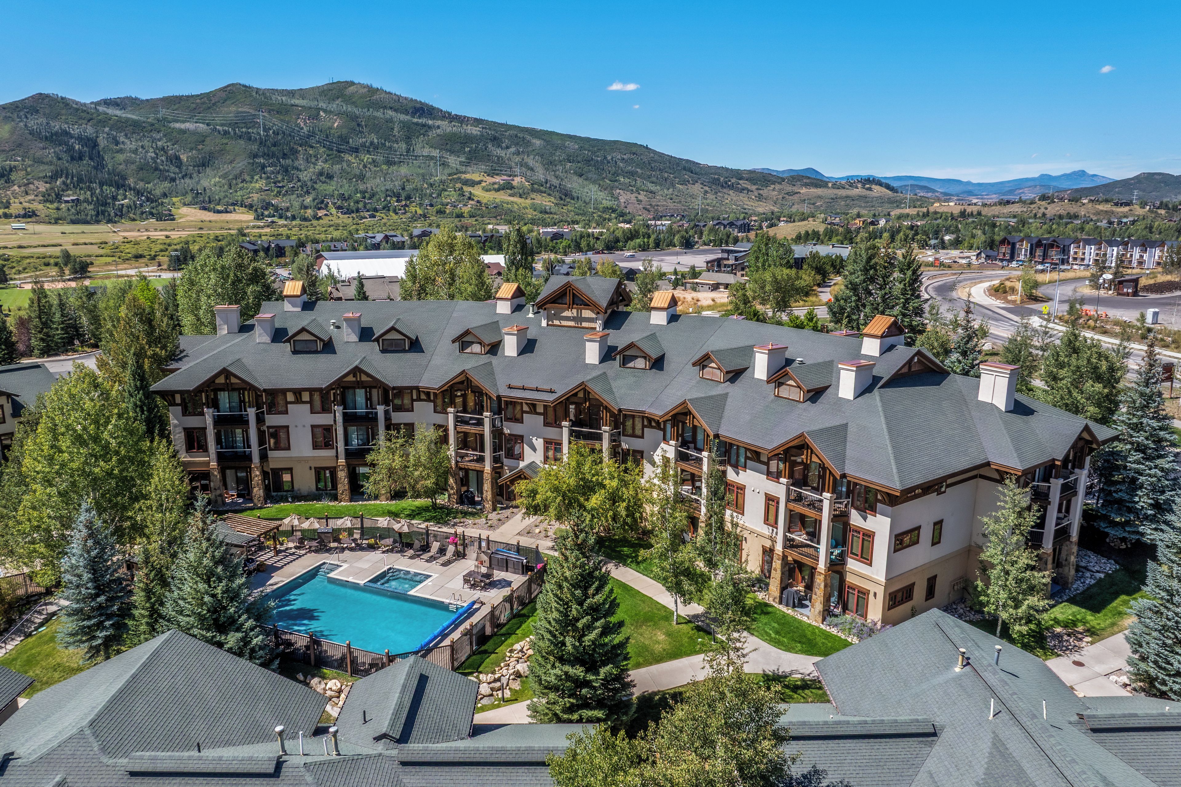 A resort with multiple buildings, a swimming pool, and a mountainous backdrop.