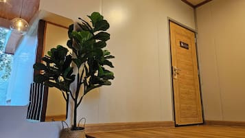 Una habitación con una puerta de madera, una planta en maceta, un banco de madera y una lámpara colgante.