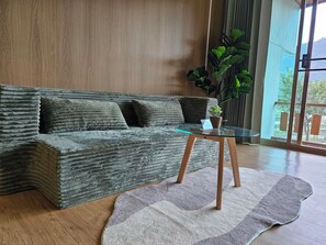 Un salon moderne avec un canapé à texture intéressante, une table basse en verre et une grande plante.