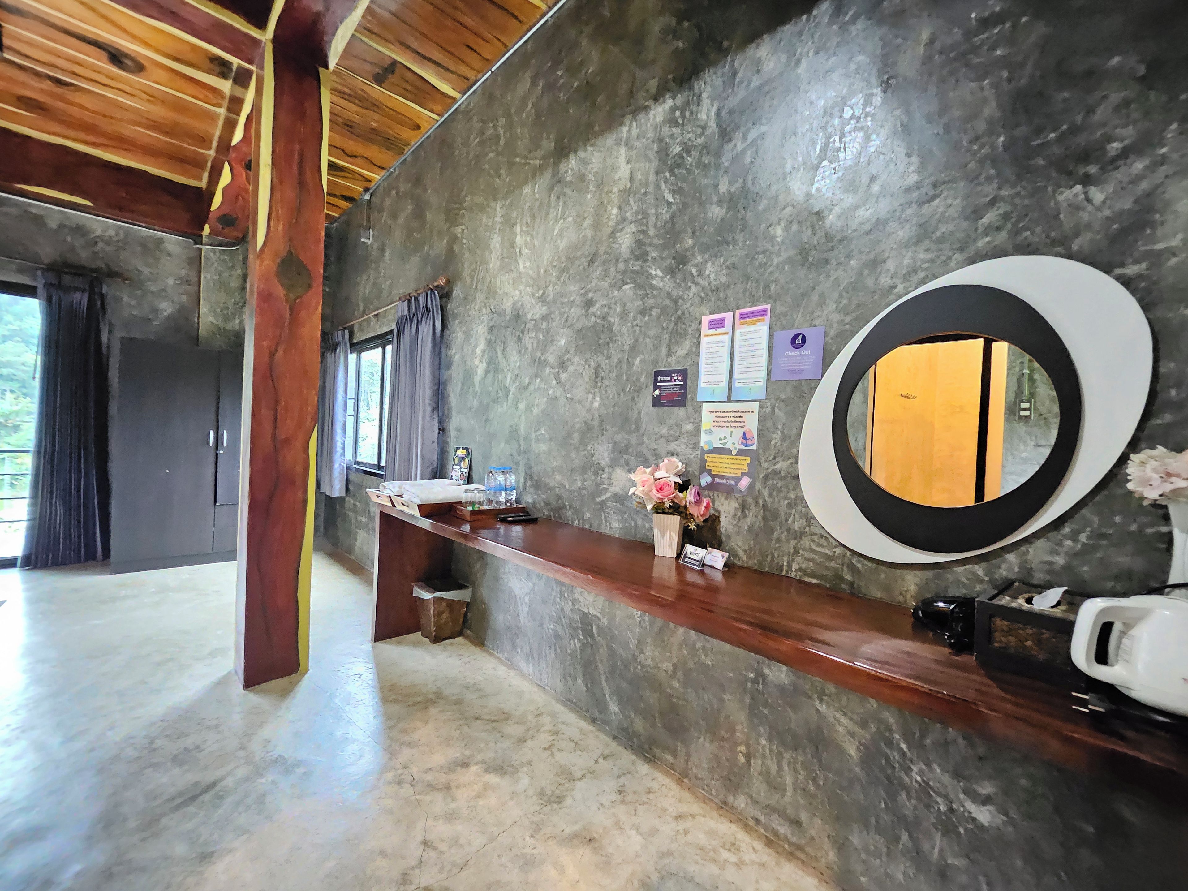 A reception area with a wooden reception desk, a large mirror, and a wall-mounted information board.