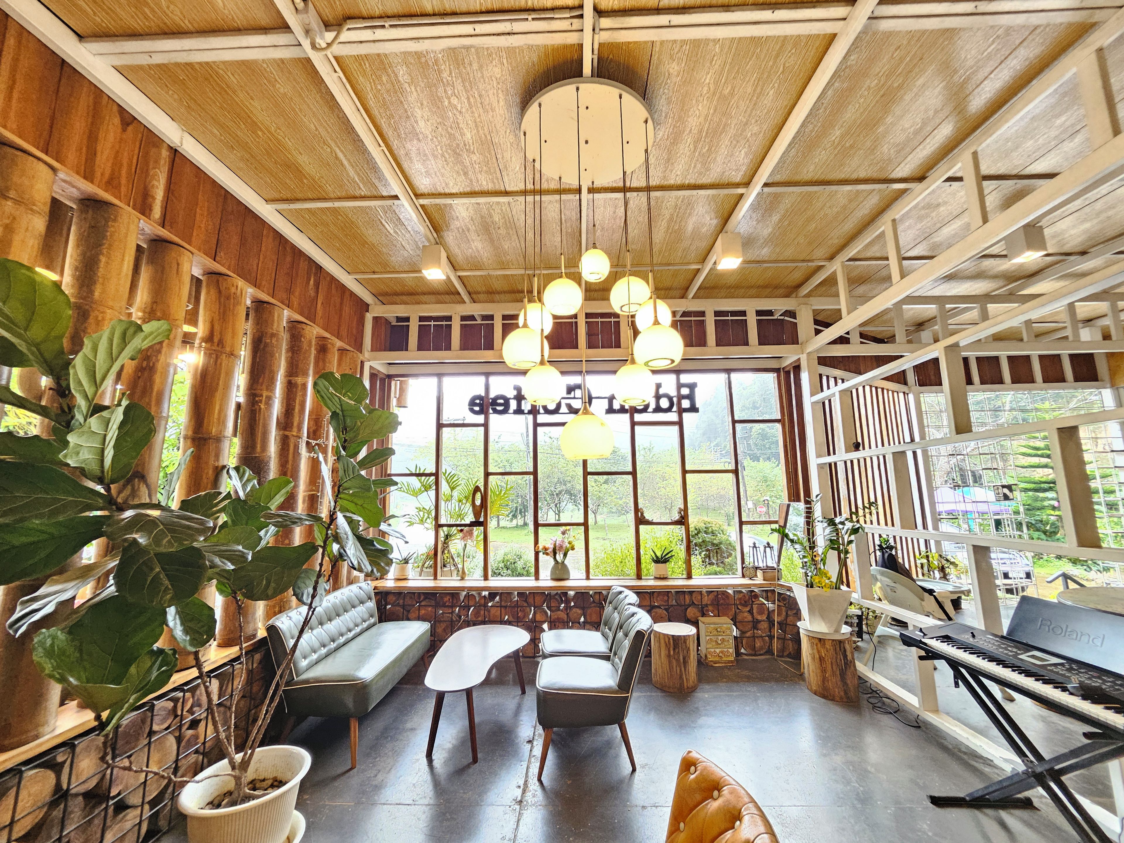 Una habitación con piano, zona de estar y ventanas amplias con vistas a la vegetación.