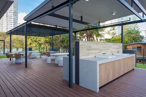 Eine Terrasse im Freien mit modernem Design, ausgestattet mit einem Holzboden, weißer Möbel und einer zeitgemäßen Theke.