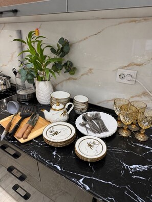 A kitchen counter with various utensils, plates, and a potted plant. - Zarafshan 49 (Tashkent)