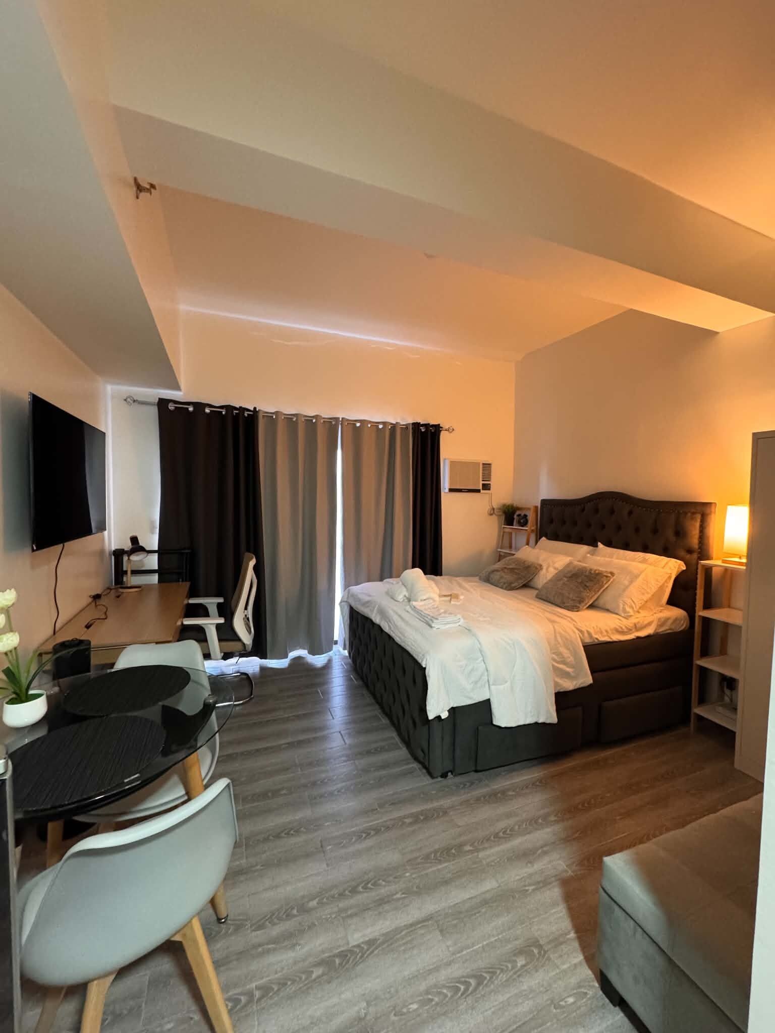Moderni hotellihuone, jossa on sänky, työpöytä, tuoli ja litteänäyttöinen televisio.