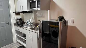 Cozinha compacta com micro-ondas, cafeteira e máquina de lavar.