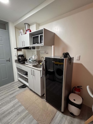 Cozinha compacta com micro-ondas, cafeteira e máquina de lavar.