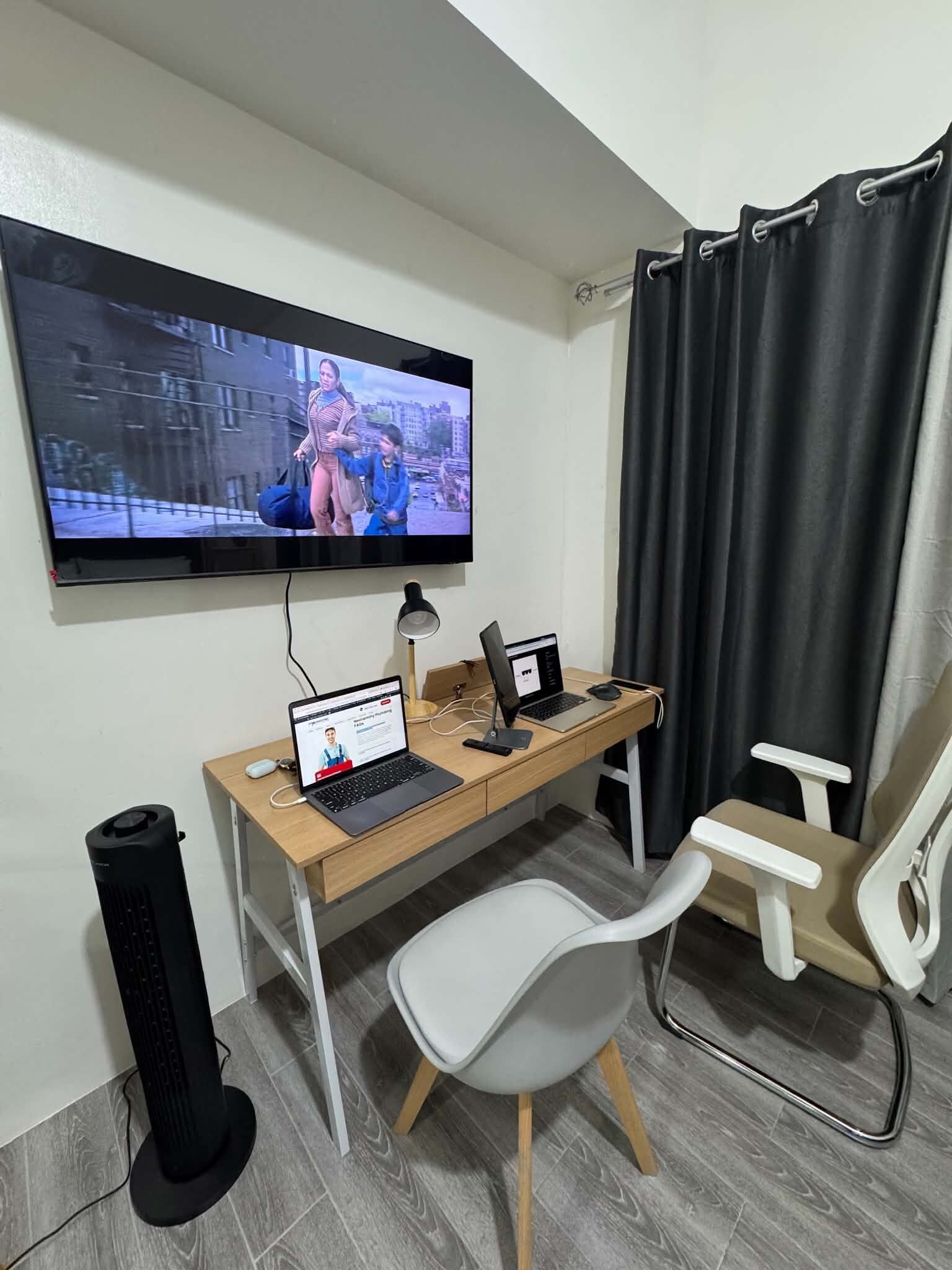 Um espaço de escritório em casa com uma mesa, dois notebooks, um computador de mesa, uma televisão e uma cadeira.