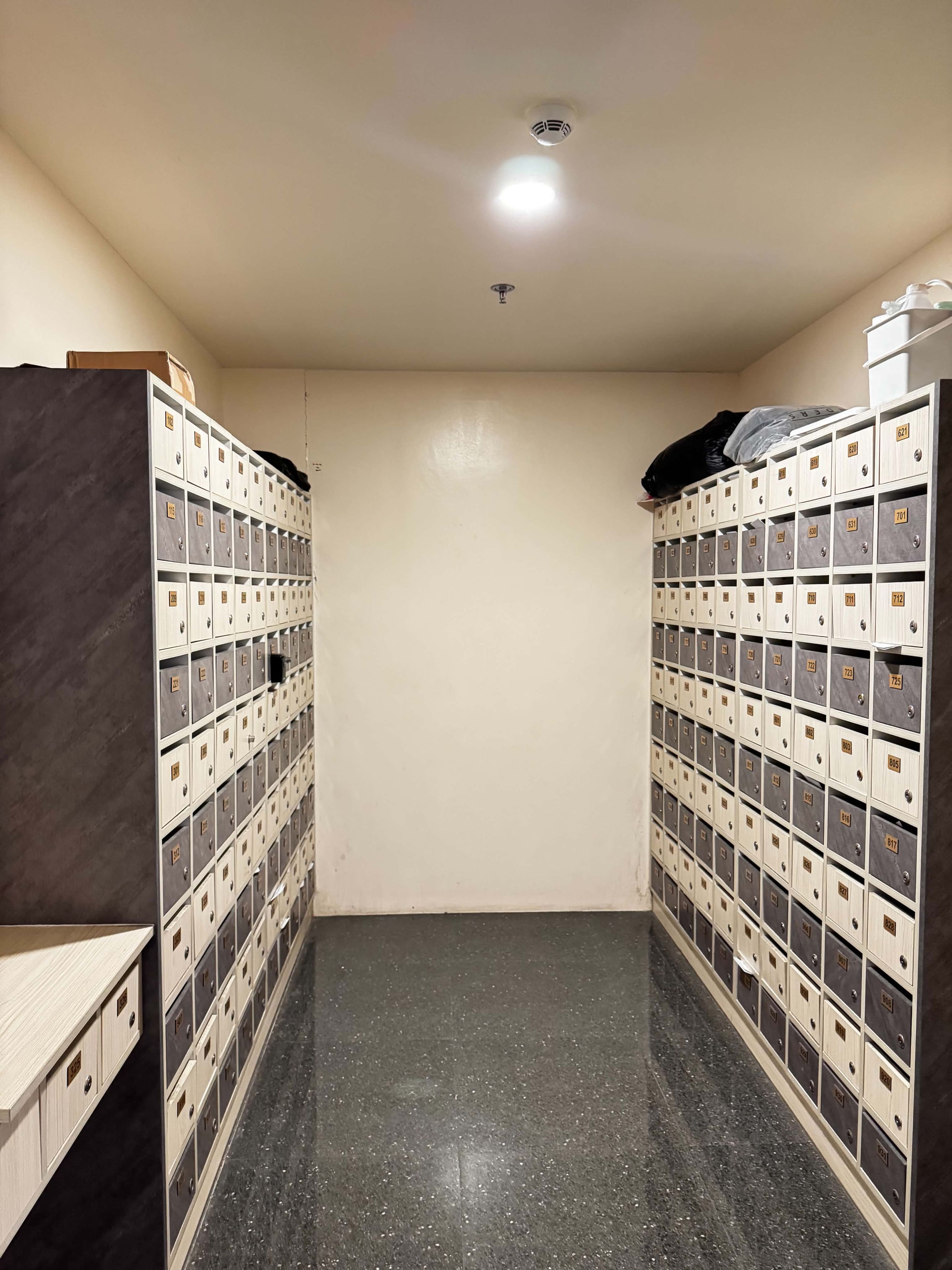 A storage room with multiple metal lockers, a tiled floor, and a ceiling light.