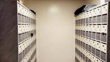 A storage room with multiple metal lockers, a tiled floor, and a ceiling light.
