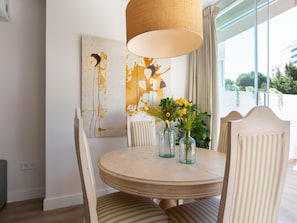 A dining area with a round table, chairs, a vase with flowers, and a painting on the wall. - Bright and spacious 2-bedroom apartment by the sea. Marbella Center. (Marbella)