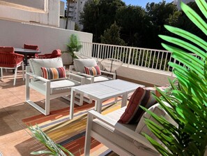 An outdoor patio area with white furniture, including sofas and a table, and a white railing. - Gardens of the Sea 332 (Marbella)