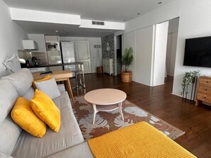 A modern living room with a sofa, a round table, and a kitchen in the background. - Gardens of the Sea 332 (Marbella)