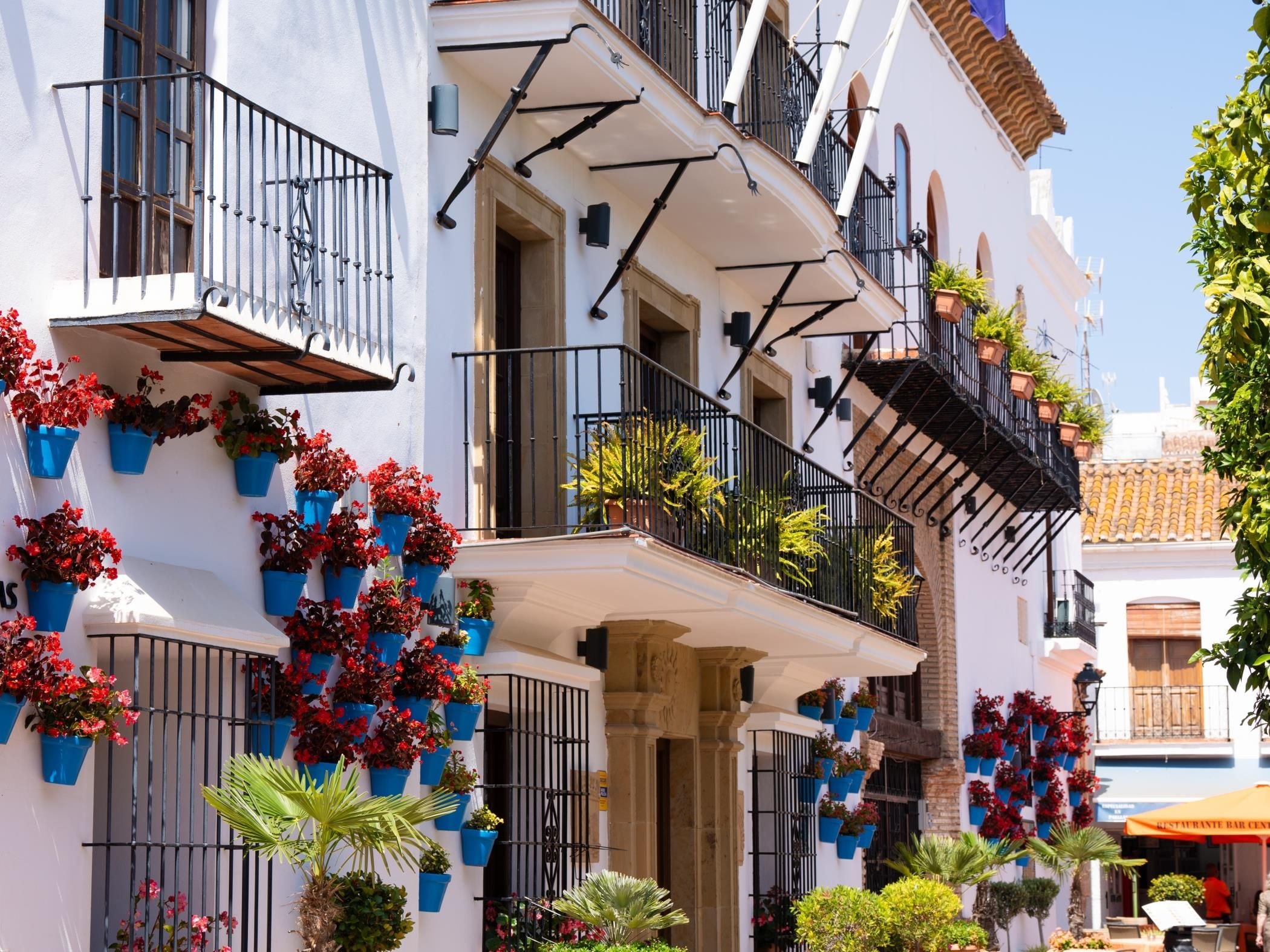 A building with multiple balconies, each adorned with potted plants and flowers.