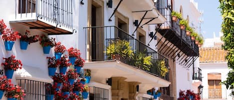 A building with multiple balconies, each adorned with potted plants and flowers.
