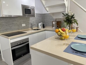 A modern kitchen with a microwave, oven, and a fruit bowl on the counter. - Beachfront duplex1 Bedroom Marbella (Marbella)