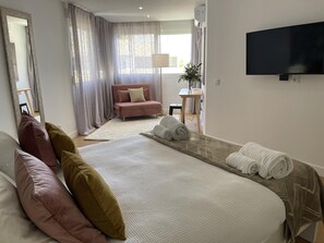 A modern hotel room with a large bed, a sofa, a TV, and a small table. - Beachfront duplex1 Bedroom Marbella (Marbella)