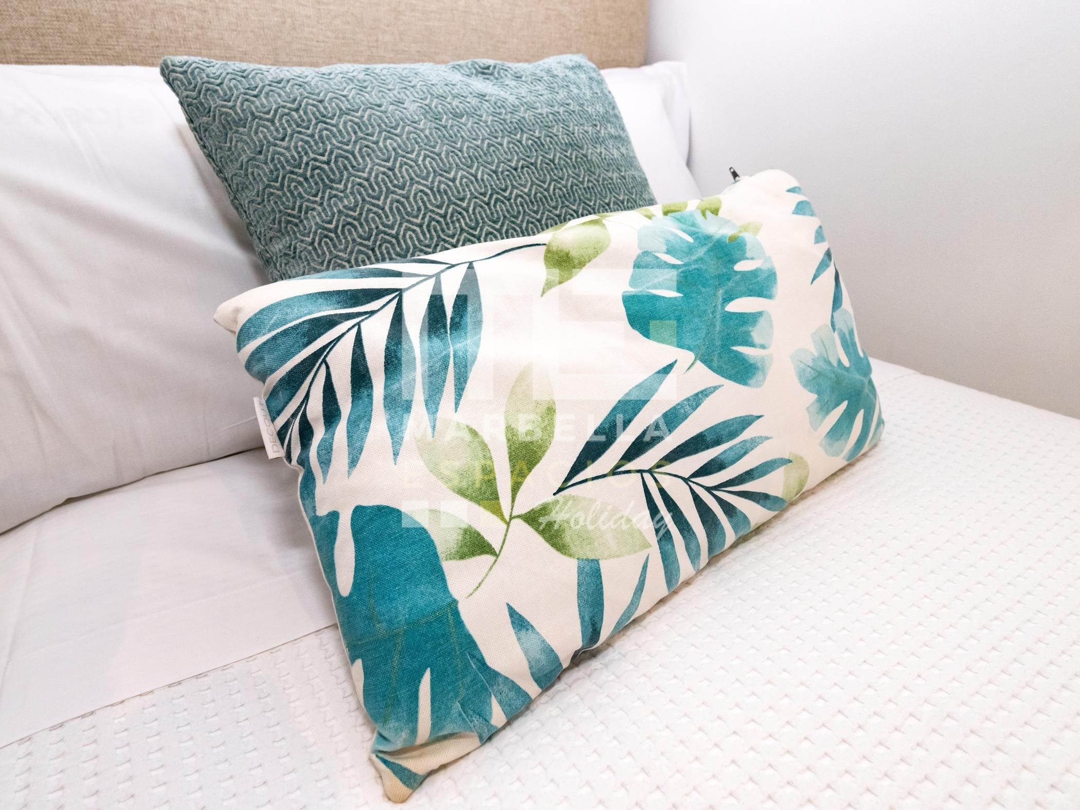 Un lit avec un oreiller à motifs et un autre oreiller orné de motifs de feuilles.
