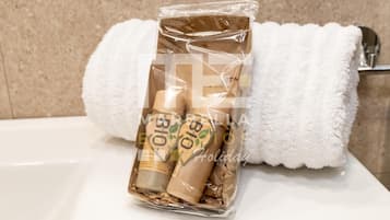 Ein Badezimmer mit einem weißen Waschbecken, einem weißen Handtuch und einer Packung Toilettenartikel.