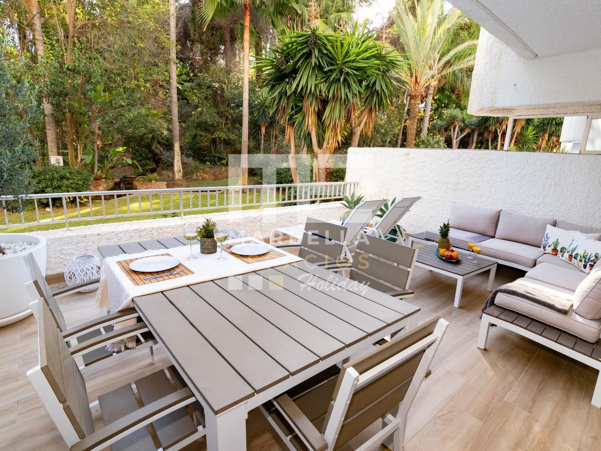 Une terrasse extérieure avec une table à manger, des chaises, un canapé et une petite table sur laquelle sont posées des boissons.