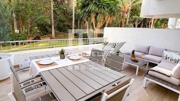 Une terrasse extérieure avec une table à manger, des chaises, un canapé et une petite table sur laquelle sont posées des boissons.