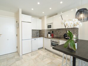 Eine moderne Küche mit weißen Schränken, einer Arbeitsplatte aus Granit und einem Essbereich mit dunklem Tisch und Stühlen.