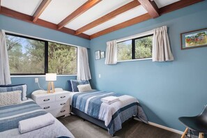 A bedroom with two beds, a desk, and a chair. - Parapara Escape Beach House (Takaka)