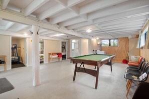 A spacious indoor area with a pool table, seating, and a wooden wall. - Parapara Escape Beach House (Takaka)