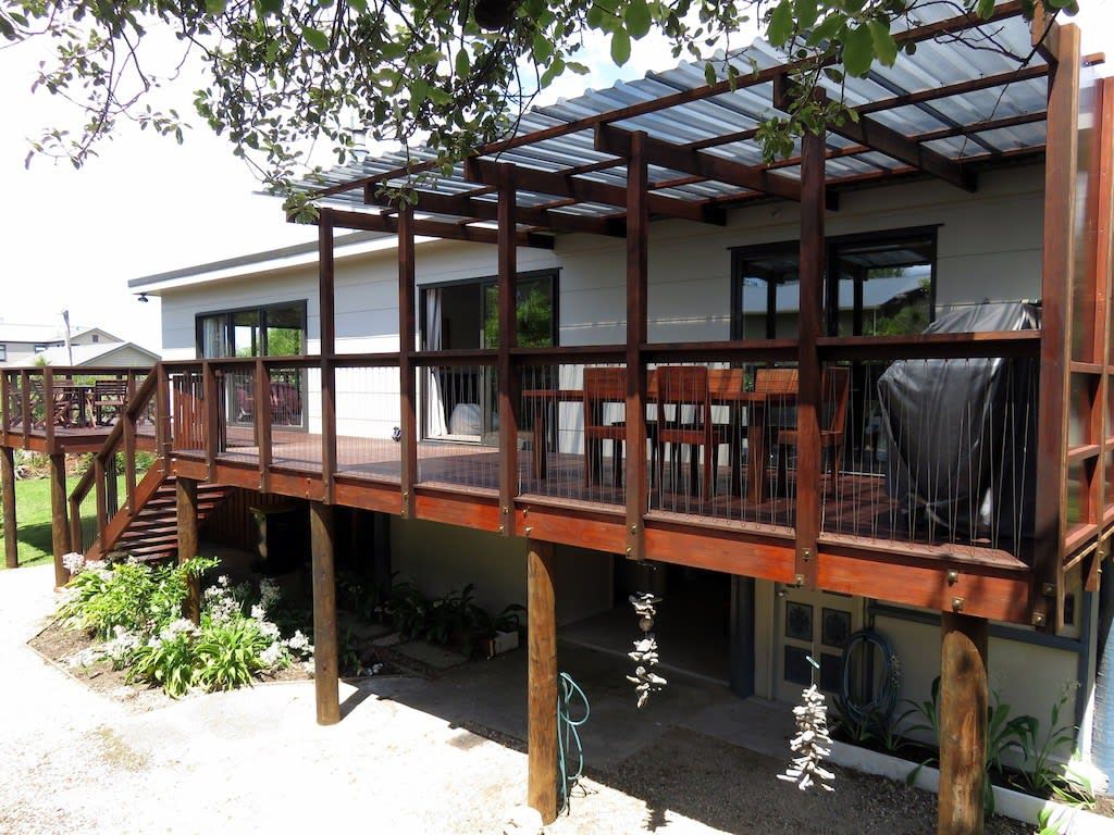 Un bâtiment à deux étages doté d’une terrasse en bois et d’un espace extérieur couvert.