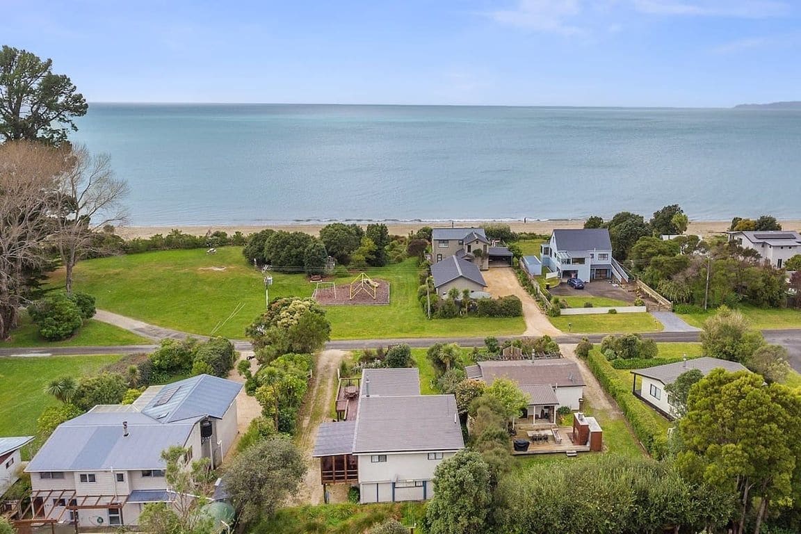Un quartier résidentiel situé sur la côte, avec des maisons, une pelouse verdoyante et une vue sur la mer.