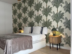 A bedroom with a bed, nightstands, and a wall with a tropical leaf pattern. - Beachside Oasis 951 Your refuge by the sea (Marbella)