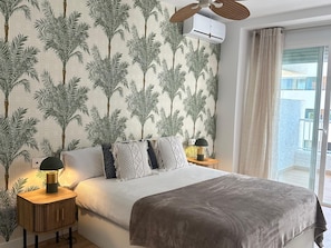 A bedroom with a bed, nightstands, a ceiling fan, and a view of the outside. - Beachside Oasis 951 Your refuge by the sea (Marbella)