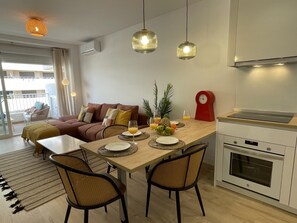 A modern kitchen with a dining area, featuring a wooden table set for two, a red clock, and a built-in oven. - Beachside Oasis 951 Your refuge by the sea (Marbella)