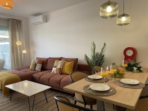 A modern living room with a brown sofa, a dining table set with plates and glasses, and a red clock on the wall. - Beachside Oasis 951 Your refuge by the sea (Marbella)