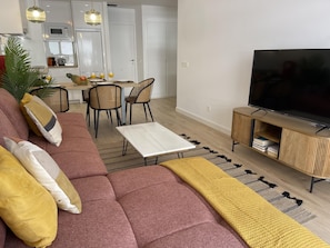 A modern living room with a sofa, television, and a dining area with chairs and a table. - Beachside Oasis 951 Your refuge by the sea (Marbella)