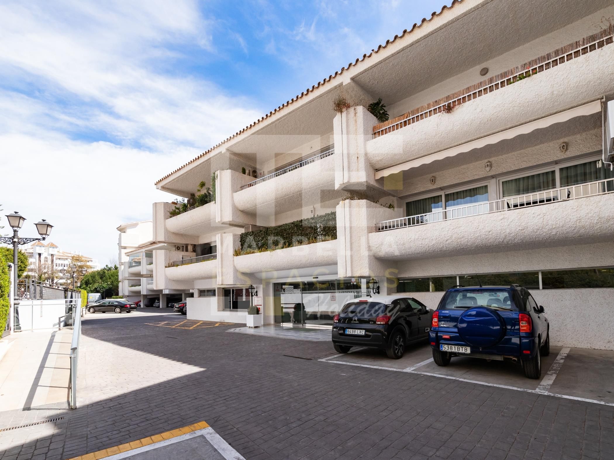 Ein mehrstöckiges Gebäude mit Parkplatz vor der Tür.
